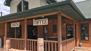 Una baita di legno con un portico su cui si leggono le scritte 'COFFEE' e 'LODGING'.