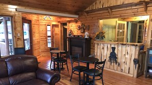 L'interno accogliente di un rifugio con un divano in pelle, un tavolo da pranzo in legno e sedie. Si scorge un camino sullo sfondo.