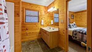 Het interieur van een houten chalet met een badkamer, inclusief een wastafel, spiegel en roldeuren.