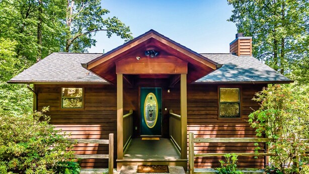 Een rustieke chalet met een houten gevel, een veranda en een groene deur.