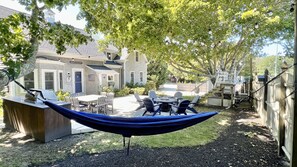 A backyard with a hammock, a barbecue grill, and a dining area with outdoor furniture. - Home Plate Nestled in Downtown Chatham! (Chatham)