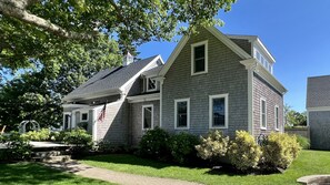 A two-story house with a gabled roof, a front porch, and a well-maintained lawn. - Home Plate Nestled in Downtown Chatham! (Chatham)