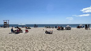 A sandy beach with several beach chairs and umbrellas, a lifeguard tower, and a small tent-like structure. - Home Plate Nestled in Downtown Chatham! (Chatham)