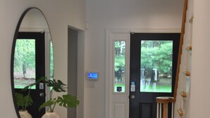 Un pasillo con un escritorio de vidrio, una planta en maceta, una puerta con ventana y una escalera.