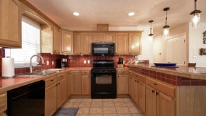 A kitchen with wooden cabinets, a black stove, a microwave, and a sink.