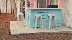 Ein kleiner Außenbereich mit Bar, gestaltet in Blau und Weiß, mit einem Holzboden und zwei weißen Barhocker.