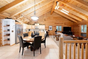 Interno di una baita di legno con zona pranzo, cucina e soggiorno.