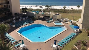 Hotellets pool med flere afdelinger, udsigt til stranden og liggestole.