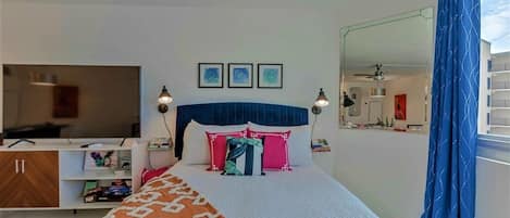 A bedroom with a bed, bedside lamps, a TV, a wardrobe, and a mirror.