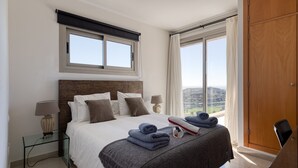 A hotel room with a large bed, a wooden wardrobe, a glass side table with a lamp, and a view of the outdoors. - Spectacular villa with private pool, sea views, barbecue and relaxing environment (San Bartolomé de Tirajana)