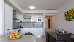 A modern kitchen with white cabinets, a microwave, and a dining area with wicker furniture. - Spectacular villa with private pool, sea views, barbecue and relaxing environment (San Bartolomé de Tirajana)