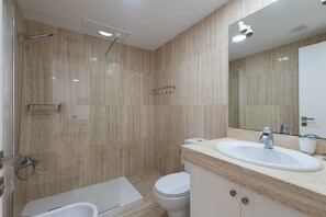 A modern bathroom with a shower, toilet, and sink.