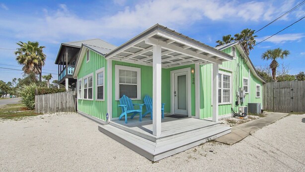 A green house with a porch and two blue chairs. - {Laguna Shores} 1 Block 2 Beach + Pool-Dogs OK (Panama City Beach)