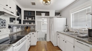 A modern kitchen with white cabinetry, a granite countertop, and a built-in refrigerator. - {Laguna Shores} 1 Block 2 Beach + Pool-Dogs OK (Panama City Beach)