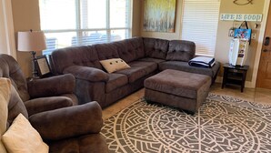 Una sala de estar con un sofá modular, un reposapiés y una alfombra estampada.