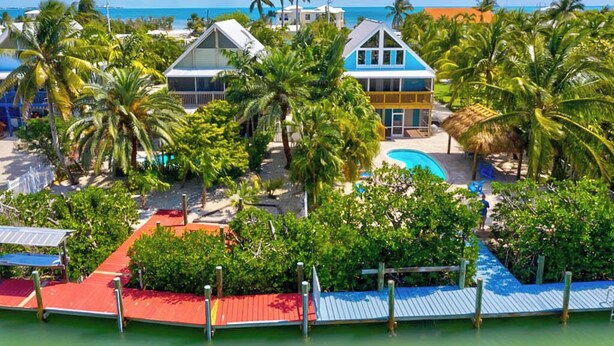 A resort with multiple buildings, a swimming pool, and palm trees. - P77 - Sombrero Beach - Pool home offering 3 bedrooms, private pool and deep water dockage! (Mararathon)