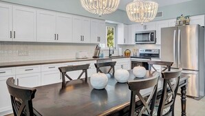 A modern kitchen with white cabinets, a dark wooden table, and two large crystal chandeliers. - P77 - Sombrero Beach - Pool home offering 3 bedrooms, private pool and deep water dockage! (Mararathon)