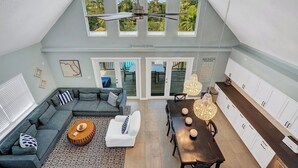 A spacious loft with a high ceiling, a dining area, a living room with a sofa and coffee table, and a kitchen with white cabinets. - P77 - Sombrero Beach - Pool home offering 3 bedrooms, private pool and deep water dockage! (Mararathon)
