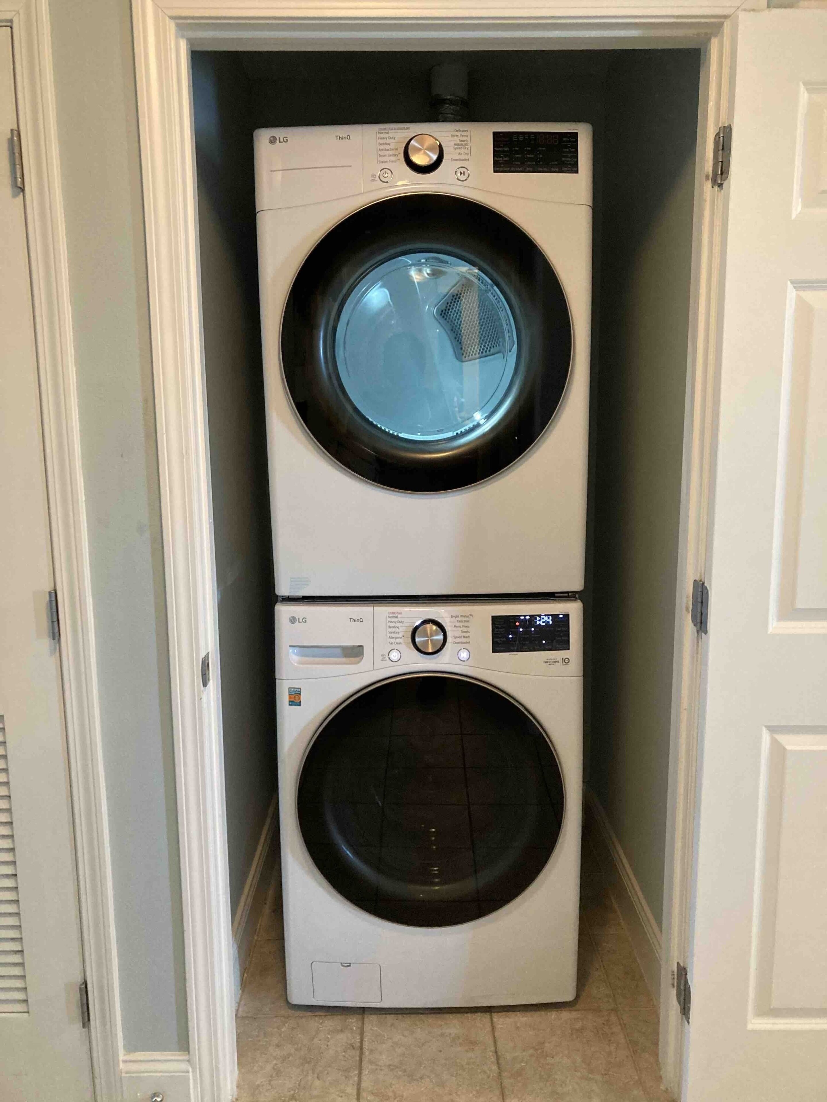A stacked washer and dryer unit in a narrow hallway.