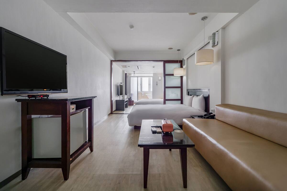 Una habitación de hotel con televisión, escritorio, sofá y cama.