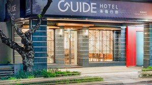 A hotel facade with a prominent sign, large glass windows, and a tree in the foreground. - Guide Hotel - Kaohsiung Shinkuchan (Kaohsiung)