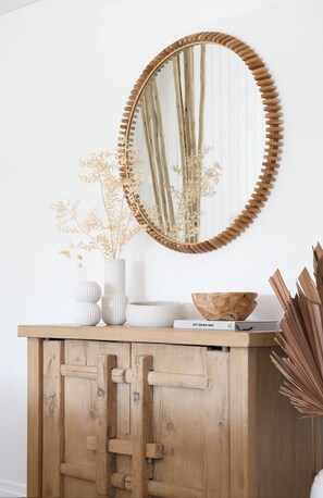 Un mueble de madera con un espejo, un cuenco y jarrones decorativos.