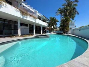 A swimming pool with a curved edge, surrounded by a white building with multiple windows and a balcony. - The Loft - 800m to Hastings St! (Noosa Heads)