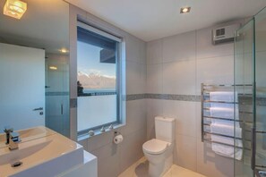 Une salle de bain moderne avec une grande fenêtre, une douche en verre et un lavabo blanc.
