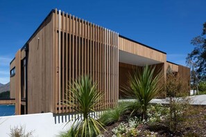 Een modern gebouw met een houten gevel, een wit balkon en uitzicht op zee.