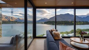 A modern interior with a large window overlooking a lake and mountains. - Lakehouse 2 – Parking, Fireplace, AC, Lake Views (Queenstown)