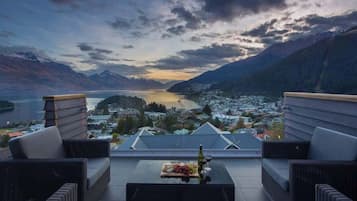 A terrace with wicker furniture, a bottle of wine, and a fruit platter.