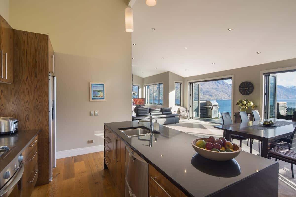 A modern kitchen with a large island, a dining area with a view, and a living space with a fireplace.