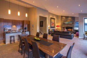 Une cuisine moderne avec des meubles en bois, un coin repas avec une table et des chaises en bois, un salon avec un canapé et une cheminée, et un escalier menant à un autre niveau.