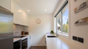 A modern kitchen with a built-in oven, a sink, and a window with a view of the outdoors. - Hillside Villa 4 – Modern 2BR Walk to Town & A/C (Queenstown)