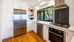 Uma cozinha moderna com eletrodomésticos de aço inoxidável, uma janela com vista e um backsplash de azulejos pretos.
