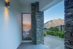 A modern exterior with a stone column, a glass door, and a view of mountains.
