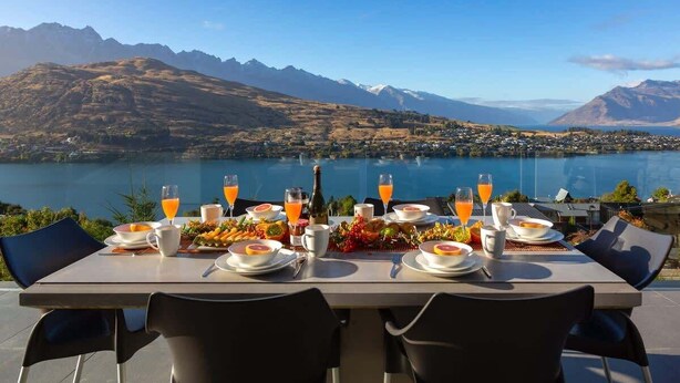 A table set for breakfast with a scenic mountain and lake view. - Aurora Lodge– Hot Tub, Fireplace & Lake Views, BBQ (Queenstown)