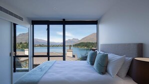 Ein Schlafzimmer mit großem Fenster, einem Bett und Blick auf Berge und Wasser.