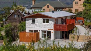 A modern two-story house with a balcony, a garage, and a view of the mountains. - Hillside Villa 3 – Modern 2BR Walk to Town & A/C (Queenstown)