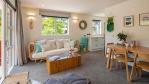 A cozy living room with a sofa, coffee table, and dining area. - Hillside Villa 3 – Modern 2BR Walk to Town & A/C (Queenstown)