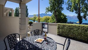 Un patio al aire libre con una mesa lista para comer, una planta en maceta y una botella de vino.