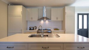 Una cocina moderna con una isla central, electrodomésticos de acero inoxidable y muebles de cocina blancos.