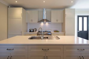 Una cocina moderna con una isla central, electrodomésticos de acero inoxidable y muebles de cocina blancos.