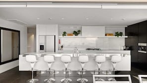 Cozinha moderna com ilha central, banquetas e geladeira.