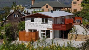 A modern house with a white exterior, a balcony, and a view of mountains. - Hillside Villa 2 – Modern 2BR Walk to Town & A/C (Queenstown)