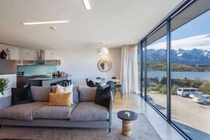A modern living room with a sofa, dining table, and kitchen area.