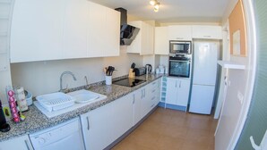 A compact kitchen with white cabinets, a granite countertop, a built-in oven, and a microwave.