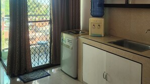 A compact kitchen with a washing machine, a water dispenser, and a sink.