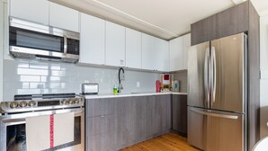 A modern kitchen with stainless steel appliances, white cabinets, and a wooden floor. - Suite 209: Beautiful 2-Bedroom Beachfront Suite (Wainfleet)