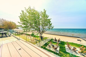 A deck with outdoor seating, a tree, and a view of the sea.